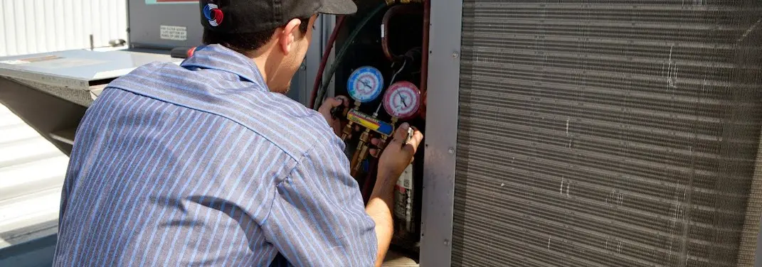 HVAC technician servicing a condenser unit in Old Forge